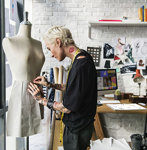 Stylish, tattooed designer working in front of window